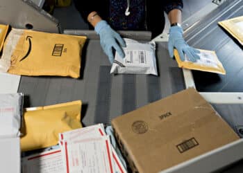 A worker sorts packages at the U.S. Postal Service processing and distribution center in Merrifield, Va. (Courtesy/Andrew Harrer/Bloomberg)